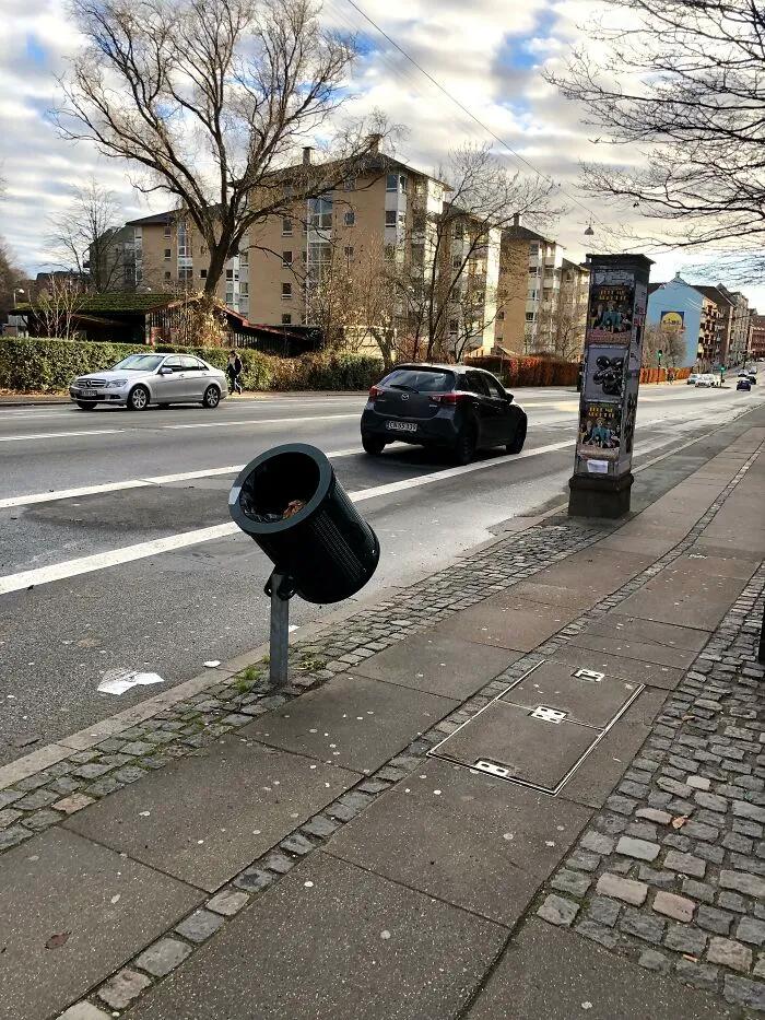 An angled trash can on a city sidewalk showing ingenious things in various parts of the world for cyclists.