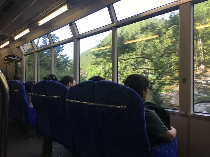 Passengers seated on a train with large panoramic windows, an ingenious transport feature.