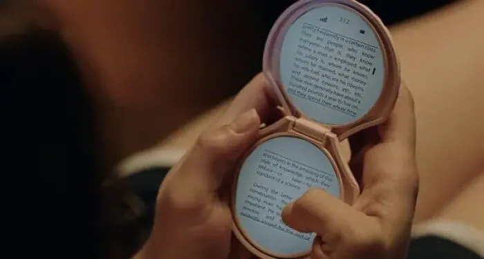 A hand holding a pink compact mirror shaped digital reader, a creative movie prop