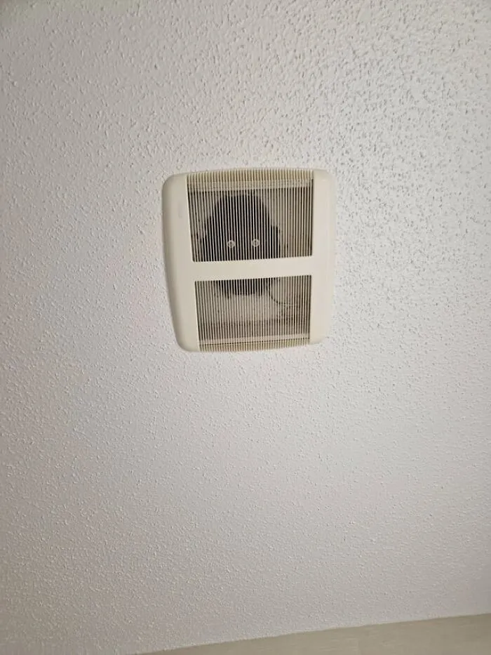 A weird and creepy photo of glowing eyes peering out from inside a ceiling air vent.