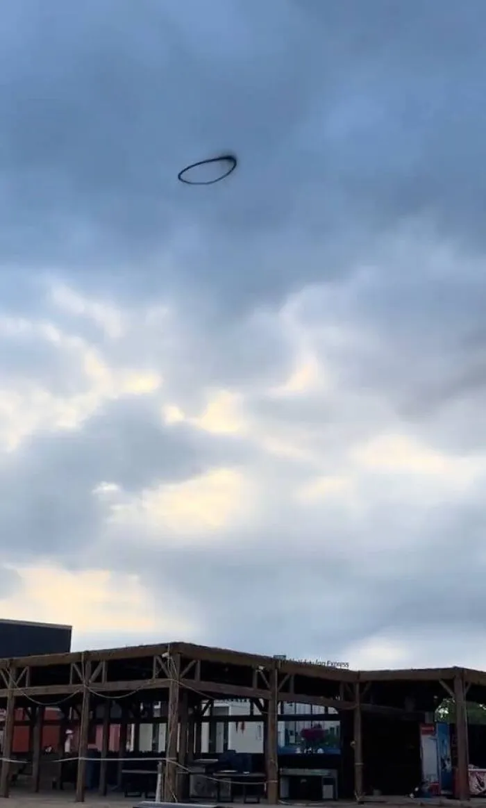 A strange black smoke ring floating above a building, making for a weird and creepy photo.