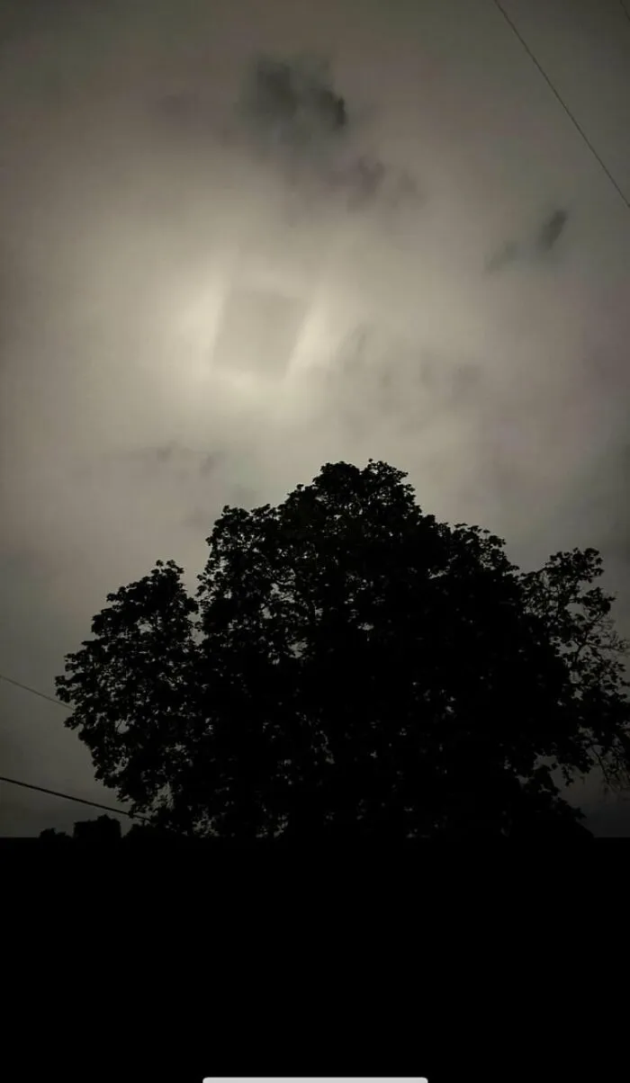 A weird and creepy photo of a strange, square-shaped glowing light in the cloudy night sky.