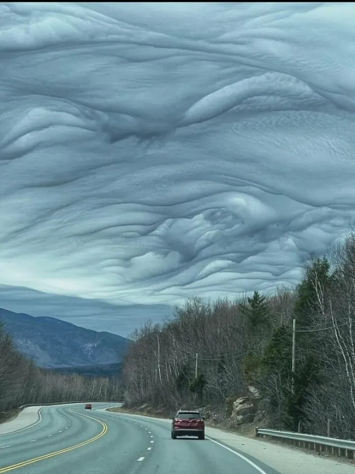 Dramatic wavy asperitas clouds rolling over a highway in creepy photos.