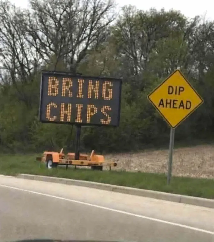 An entertaining sign on the side of the road reading, Bring Chips, next to a Dip Ahead sign.