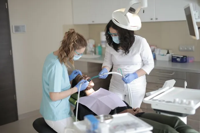 Dental professionals performing teeth cleaning on patient