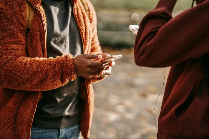 People using smartphones while standing outdoors