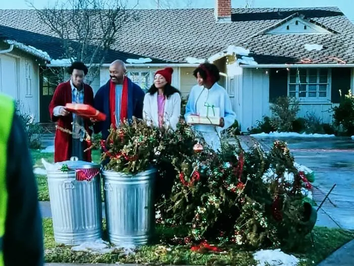 A family posing by trash cans full of holiday decorations, showing advertising fails.
