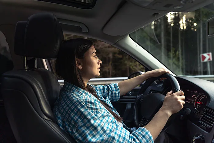 A worried woman driving a car in a worst-case scenario situation.
