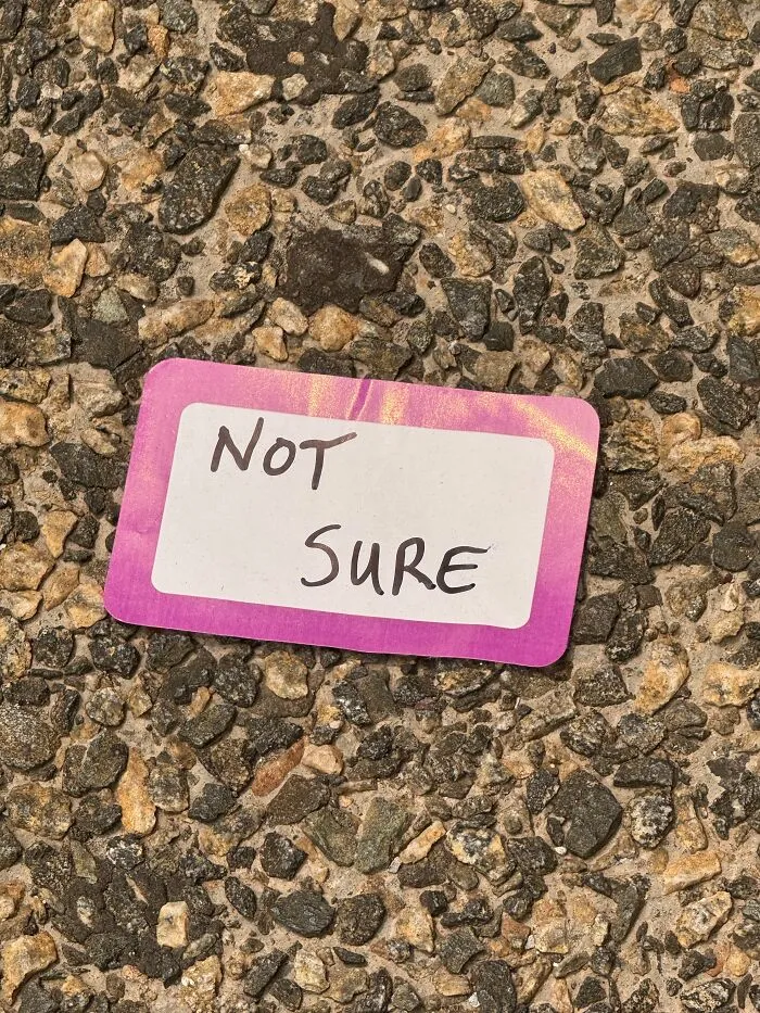 Found paper sticker on coarse stone ground reading NOT SURE