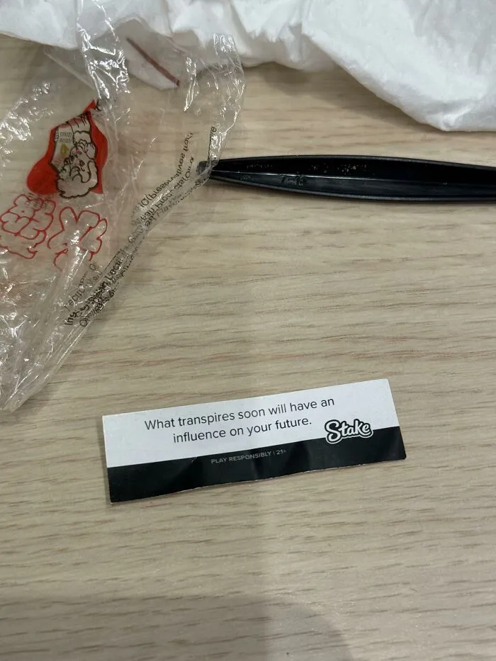A fortune cookie paper sponsored by a gambling site placed on a table, showcasing advertising fails