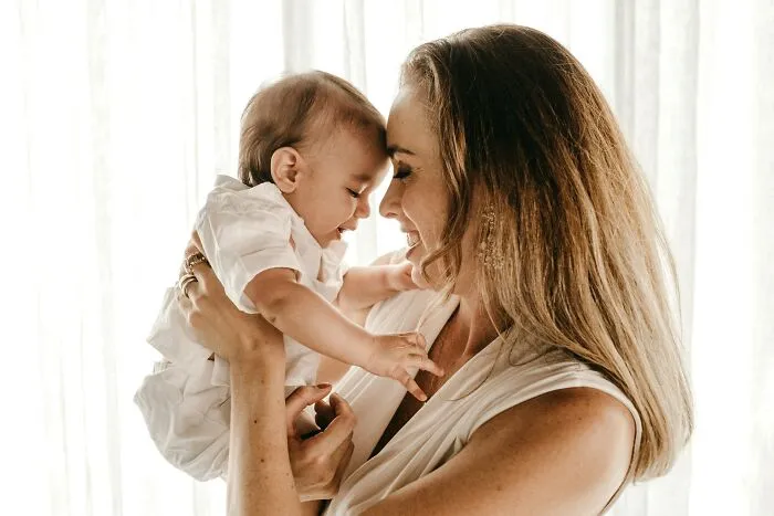 A happy mother holding her baby, representing positive behaviors they refuse to tolerate losing