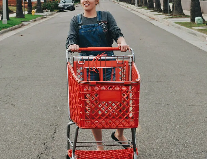 Young woman pushing shopping cart in quiet street, referencing Karen stories