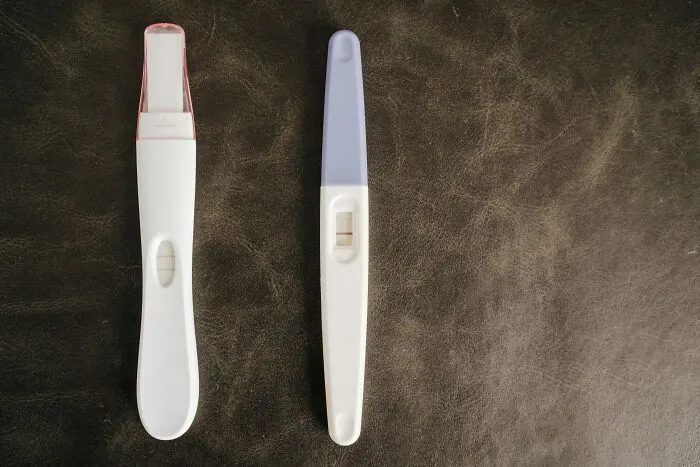 Two positive pregnancy tests lying on a dark surface, reflecting moments involving narcissistic parents.
