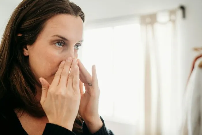 Woman touching her nose while reflecting on infuriating stories about health and wellness.