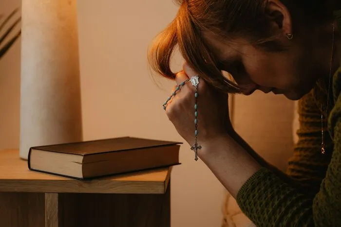 A woman prays with a rosary, reflecting on behaviors that women refuse to tolerate