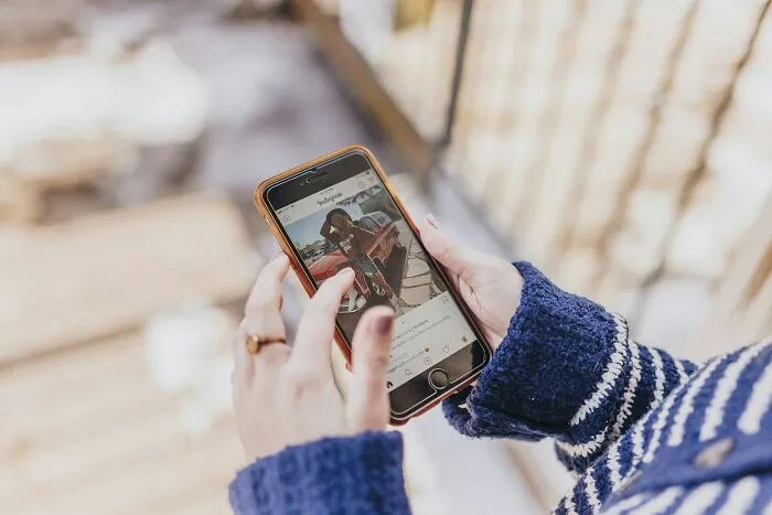 A person holding a smartphone, looking at social media, which often sparks petty relationship fights
