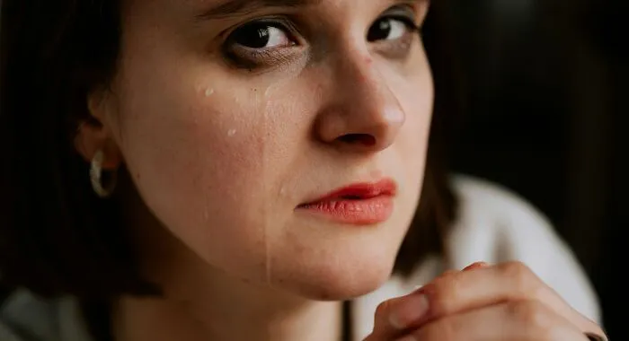 A close-up of a young woman crying with tears on her cheek, showing emotional impact from narcissistic parents.