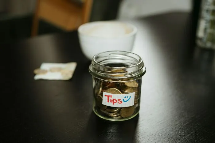Tip jar filled with coins on cafe table closeup