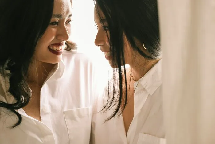 Two women smiling closely together, representing positive connections women refuse to tolerate losing