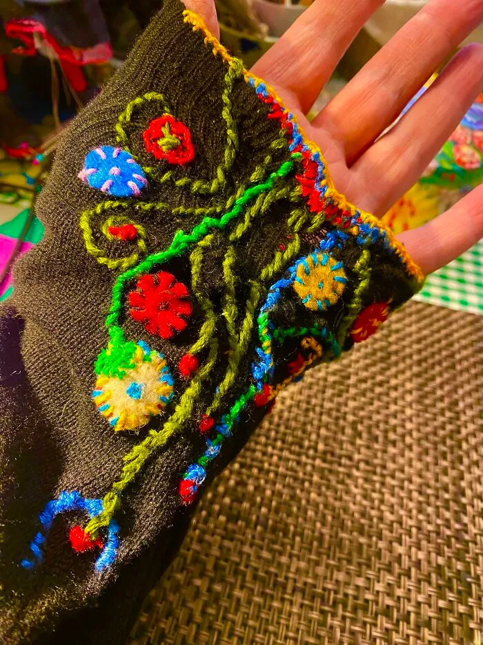 A black sleeve decorated with colorful embroidery, showing how creativity can save money on clothing repairs.
