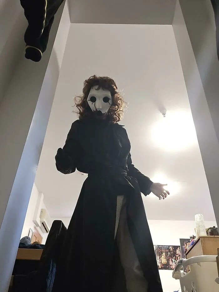 Scary masked figure wearing a long black coat for a creative Halloween costume