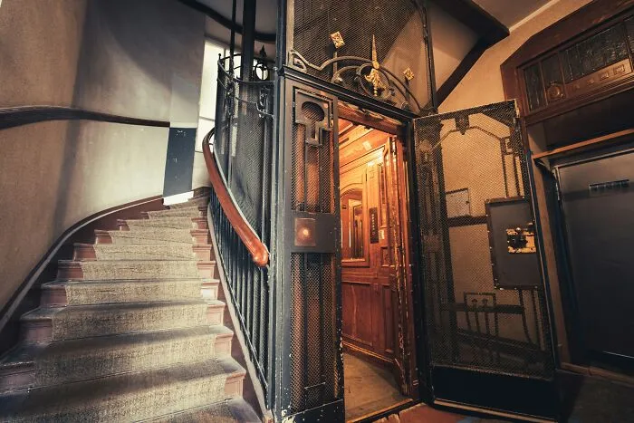 Old vintage elevator door open near spiral staircase depicting scary historical building moments