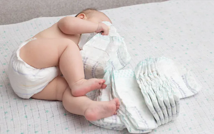 A baby lying on a bed surrounded by diapers, representing a medical story about pediatric care.