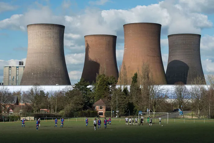 Football players under cooling towers creating surreal glitch scene