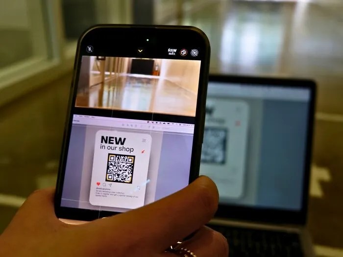 Person scanning QR code on a laptop screen with a phone, illustrating life-changing tech tips.