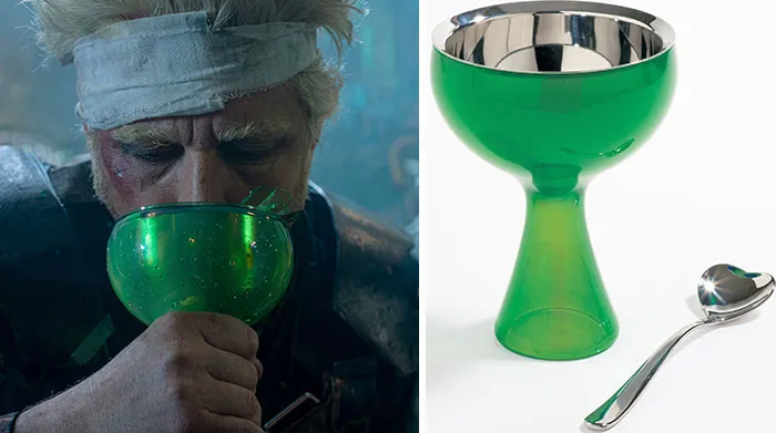 A character drinks from a green glass cup used as a creative movie prop in a sci-fi film.
