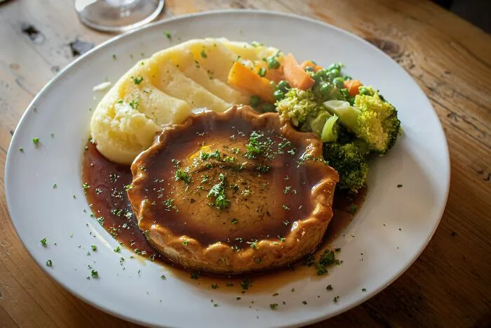 A meat pie served with mashed potatoes and vegetables, highlighting partner's funny culinary misunderstandings