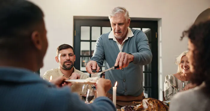 An older man serving food to family members, illustrating interactions with narcissistic parents.