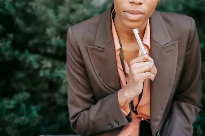 A thoughtful person holding a pen while contemplating important life and wedding decisions.