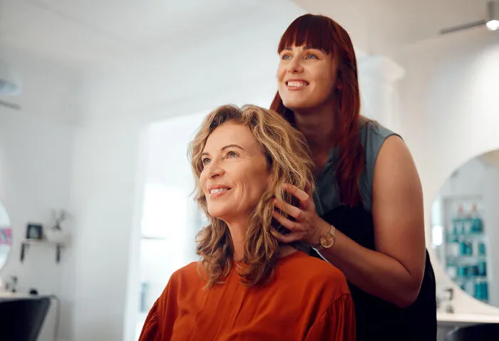 A hairstylist adjusting a woman's hair, representing the subtle art of intelligent insults