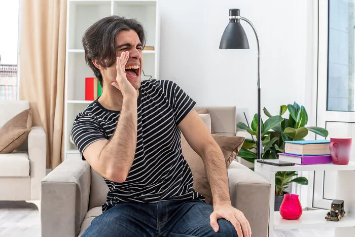 A man yelling while sitting in an armchair, illustrating a moment of intelligent insults.