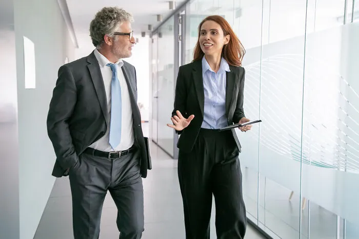 A woman in a suit talking with a colleague, reflecting the concept of intelligent insults in professional settings.