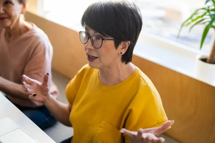 A woman gesturing while speaking, giving what might be intelligent insults.
