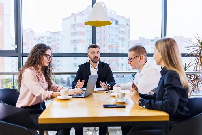 Business professionals in a meeting room, sharing intelligent insults in a professional setting