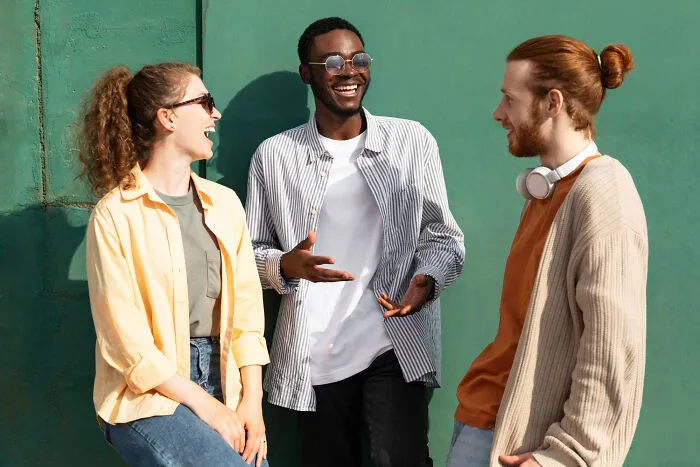 Three friends laughing together outdoors, representing intelligent insults that are subtle