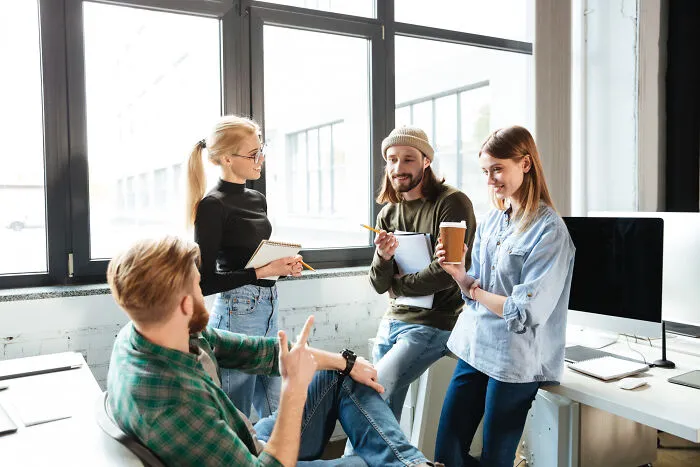 A group of coworkers chatting in an office, discussing examples of intelligent insults