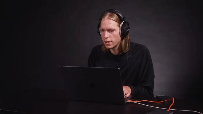 A person wearing headphones looking at a laptop, reading witty examples of intelligent insults