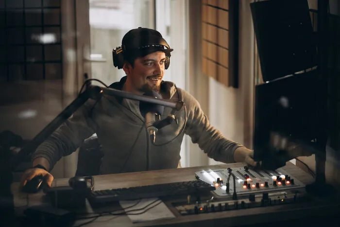 A man smiles into a microphone in a podcast studio, representing intelligent insults shared online