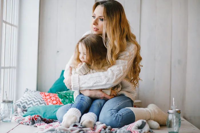 Concerned mother hugging her young daughter tightly, fearing situations where people get disowned