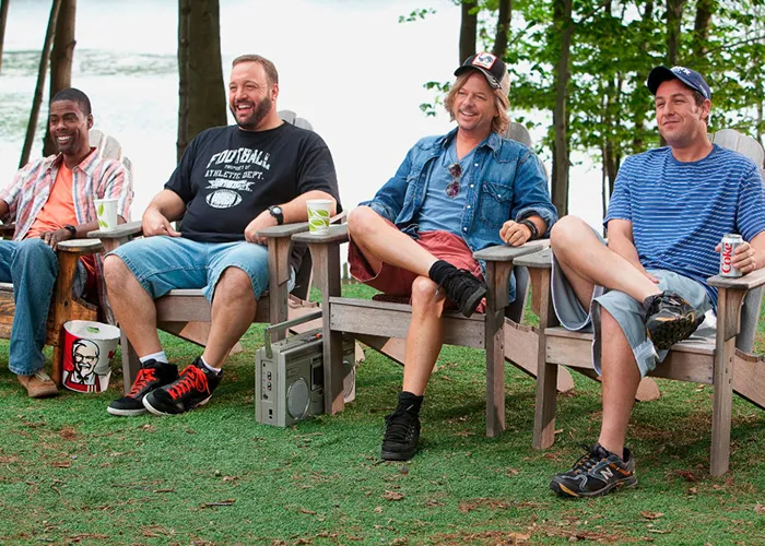Adam Sandler relaxing outdoors in lawn chairs with cast members from his films.