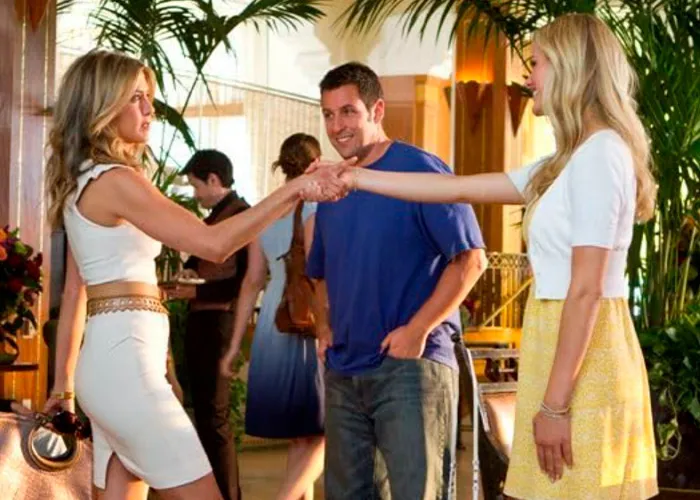 Adam Sandler standing between two women shaking hands in a movie set scene.