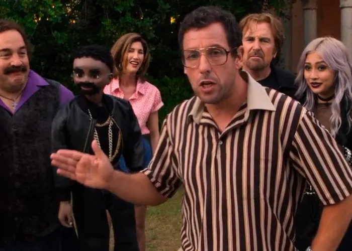 Adam Sandler wearing glasses and speaking animatedly in a movie scene