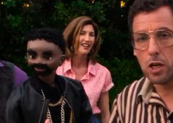 Adam Sandler wearing glasses and speaking animatedly in a movie scene