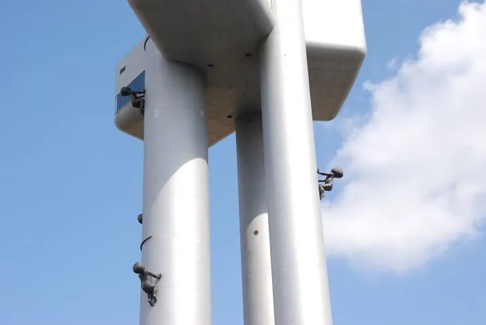 Metallic towers with human figures climbing strange buildings