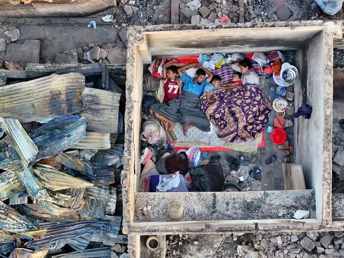 Family resting in small walled area amid ruins and debris