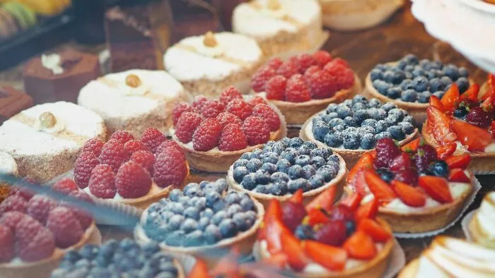 A variety of brilliant tips fruit tarts filled with raspberries and blueberries on display.